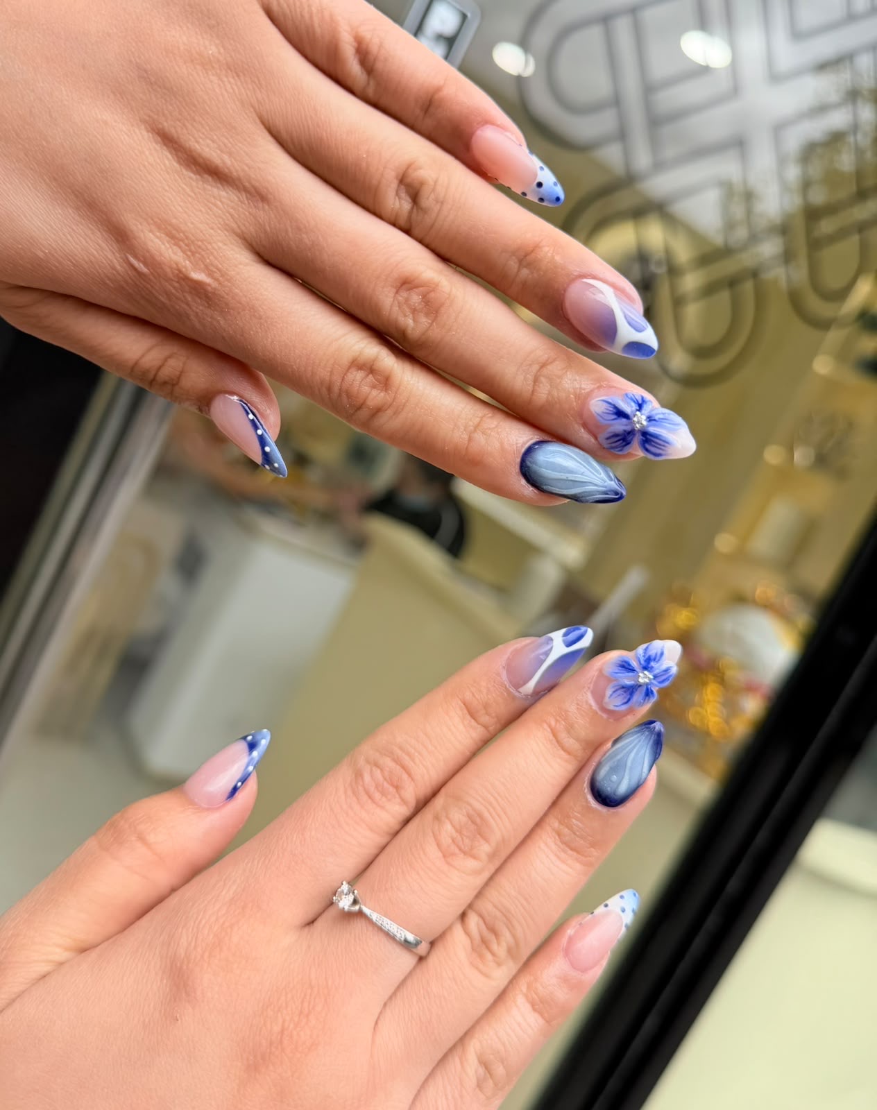 Blue and white marble and floral nail art beside the salon's glass front