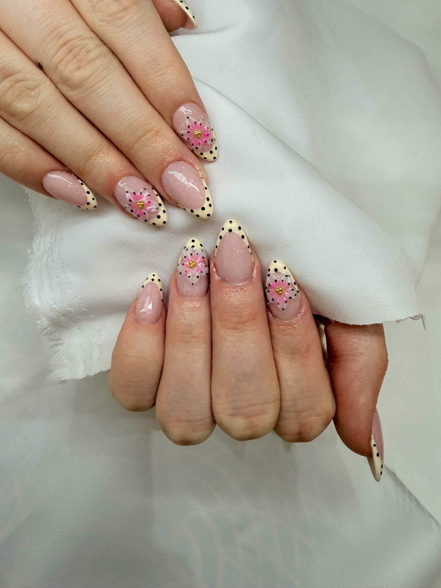 Pale yellow French tips with fine polka dots and a 3D pink flower
