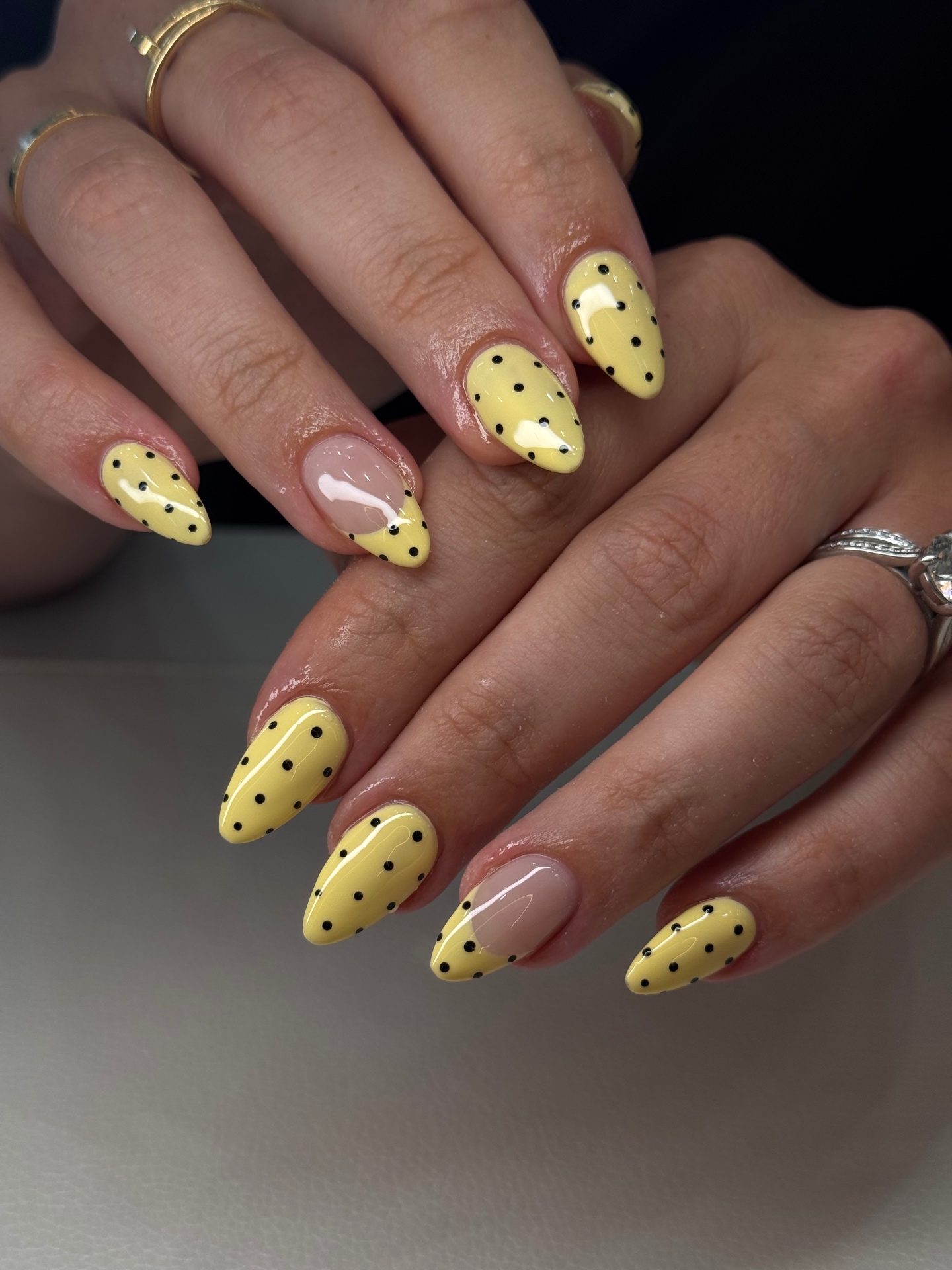 Butter yellow almond nails with fine black polka dots and nude negative-space French